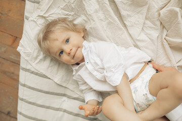 Happy toddler boy lies on bed.