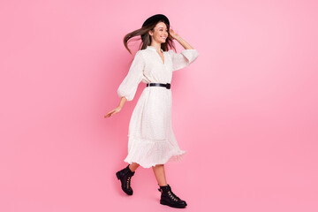 Photo of pretty charming young woman dressed white clothes cap walking air blowing isolated pink color background