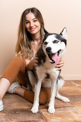 Young pretty woman with her husky dog sitting in the floor at indoors