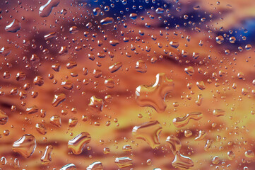 Abstract image with raindrops on glass on a sunset background