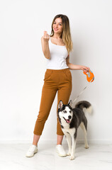 A full length young pretty woman with her dog making money gesture