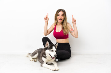 Young sport girl with her dog sitting on the floor pointing up a great idea