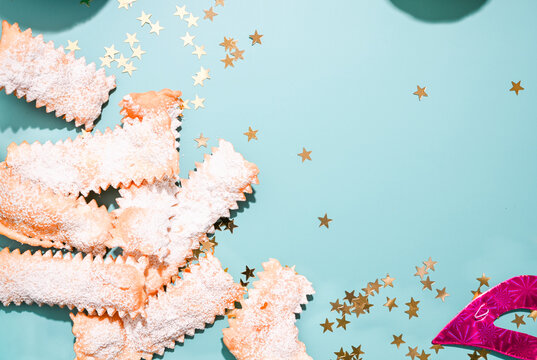 Carnival food TYPICAL. Sfrappole or chiachiere or angel wings on a blue background. Traditional sweet crisp pastry deep-fried and sprinkled with powdered sugar. Copy space