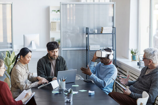 Portrait of diverse IT team developing software for virtual reality project, focus on African-American man using VR in office