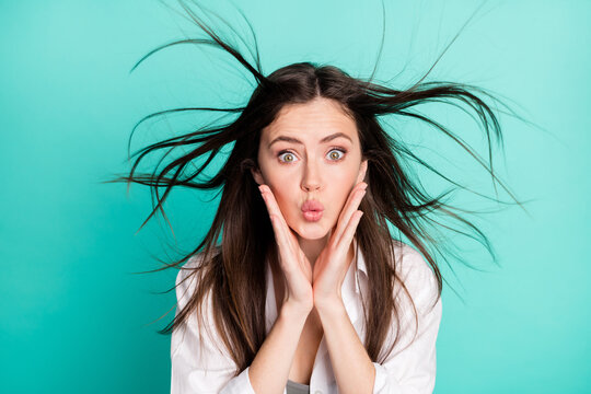 Photo of funky charming pretty nice young woman fly hair wind hold hands cheeks send air kiss isolated on teal color background