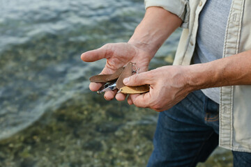 Man with fishing lures on river bank, closeup