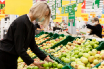 Customers in the fruit section of the store. Blurred.