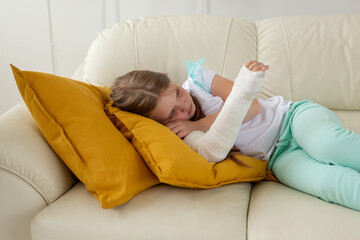 Child with a cast on a broken wrist or arm lying on a couch. Recovery and kid concept.