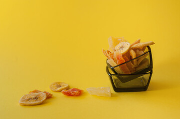 Mixed dried fruits - banana, mango, papaya. The concept of healthy food, diet. Organic sweets and snacks. Yellow background. Selective focus