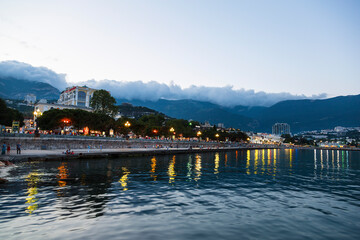 Obraz premium View of the evening embankment in Yalta with walking tourists. Crimea, Russia