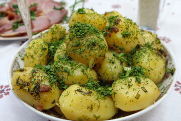Boiled potatoes with green dill on a plate, close-up