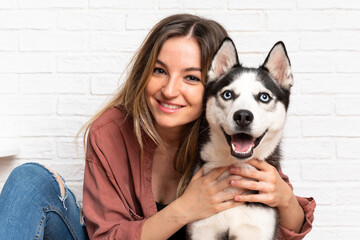 Young pretty woman with her husky dog sitting in the floor at indoors © luismolinero