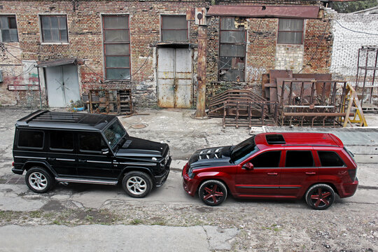 Kiev, Ukraine - September 8, 2013: Red Jeep Grand Cherokee SRT8 and Mercedes Benz G500 on the background of ruins and old buildings