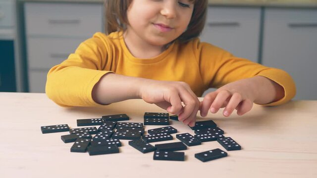 game of dominoes. Kid plays dominoes at the table. Have fun together at home