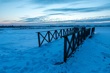 Wooden pier and a frozen lake after sunset