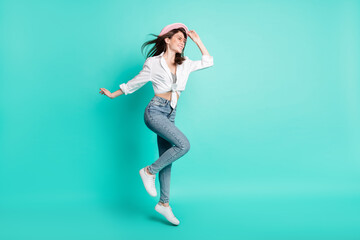 Photo of sweet cute lady wear shirt spectacles arm headwear jumping high looking empty space isolated turquoise color background