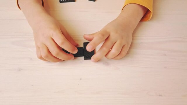 game of dominoes. Kid plays dominoes at the table. Have fun together at home