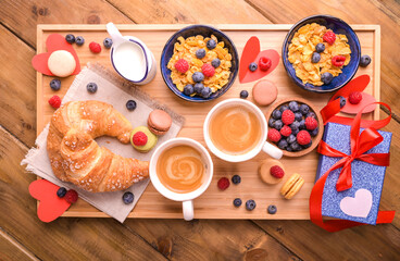 Sweet surprise in Valentine's Day. Breakfast for a couple of lovers. Aromatic coffee, muesli with berries and sweet pastries on a wooden table. Above. High quality photo