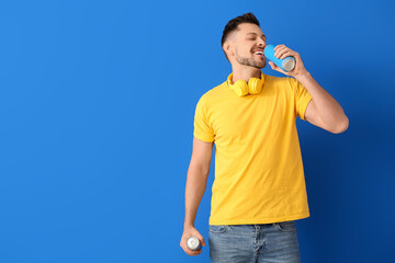 Handsome man drinking soda on color background