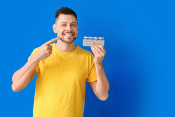 Man with teeth color chart on blue background