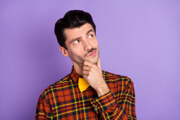 Photo of minded pensive guy finger chin look empty space wear bow tie checkered shirt isolated purple background