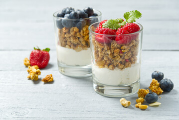 Yogurt with granola and fresh blueberries and raspberry, in glass. Healthy breakfast: yogurt parfait with granola and berries