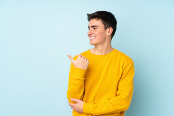 Teenager caucasian handsome man isolated on purple background pointing to the side to present a...