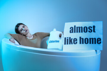 Young woman with bottle of chlorine in bathtub. Concept of cruelty to animals