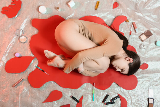 Young woman with cosmetics lying on floor in laboratory. Stop animal testing