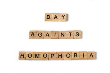 Top view of words day againts homophobia made of square wooden tiles with the English alphabet scattered on a white background with space for text. The concept of thinking development, grammar.