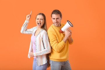 Emotional young couple with megaphone on color background