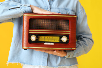 Young woman with retro radio receiver on color background