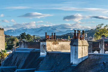 French town Pau roofs with chimneys against the winter Pyrenees mountains peaks
