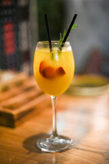 a glass with a yellow drink with fruit in it on a luminous background 