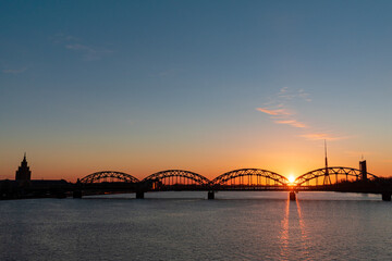 Fototapeta na wymiar Colorful sunrise over the Daugava river and the Railway bridge with the tallest tower in the European Union - Radio and TV tower in Riga, Latvia