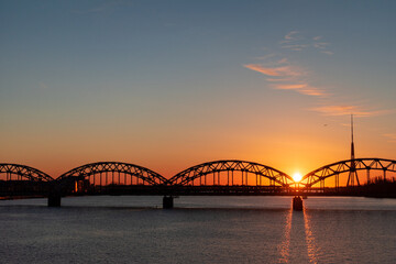 Fototapeta na wymiar Colorful sunrise over the Daugava river and the Railway bridge with the tallest tower in the European Union - Radio and TV tower in Riga, Latvia