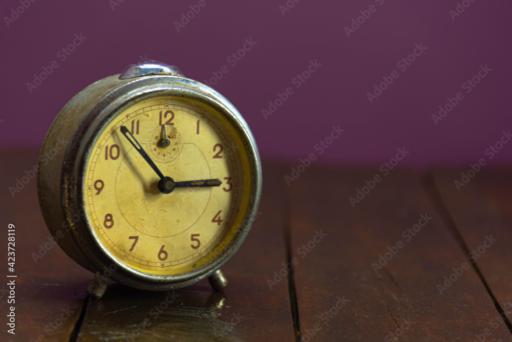 Wall mural Old and retro alarm clock on wooden surface