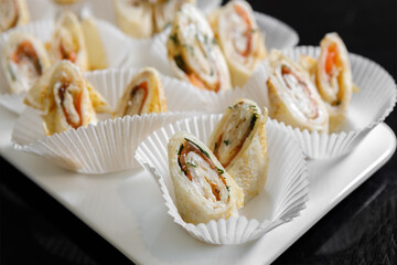 Stuffed pancakes on a platter in paper cups.