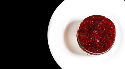 Sponge cake on a plate covered with raspberry jelly on top.