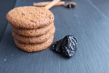 Eating still life cookie oatmeal homemade with prunes and cinnamon sticks lies a stack of slides on a black background with room for text copyspace