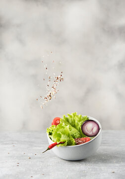 bowl with fresh lettuce and seeds in levitation on gray stone background