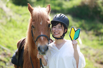 Obraz premium 初心者マークを持つ女性と馬 乗馬イメージ