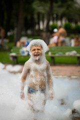 children at sea, happy boy participates in a foam party on the beach, focus