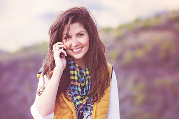 Naklejka premium Portrait of Beautiful Smiling Woman Talking on the Phone Outdoor in the Mountain 