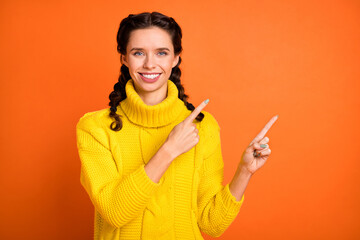Portrait of brown hair optimistic girl point empty space wear yellow sweater isolated on orange color background