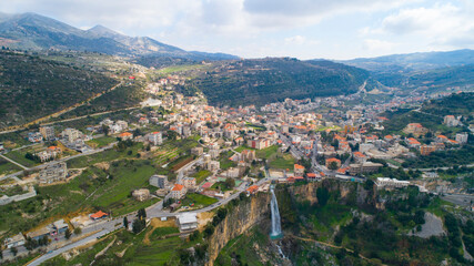 Fototapeta na wymiar Beautiful village near the forest. Aerial shot of the city and waterfall. The environment. Best hiking trails. Middle East region. Summer season in Lebanon. Cascade