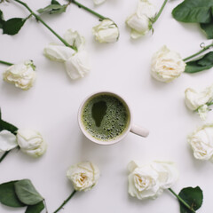 Beautiful composition with cup of matcha tea and flowers on white background. Flatlay, top view