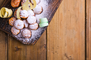 Baked castagnole with powdered sugar and confetti on a wooden table. Street food, round biscuits with sugar for the carnival of Venice. Traditional sweet pastries during the carnival. copy space