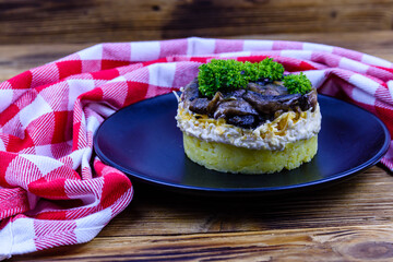 Salad with roasted mushrooms, eggs, boiled potato, cheese and mayonnaise on a wooden table