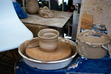 Unfinished cup from Raw clay stands on a potter's wheel. Pottery. Traditional craft